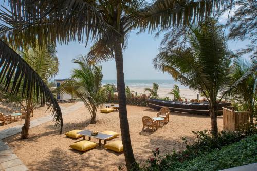 a table and chairs and a boat on the beach at Mandrem Beach Resort, a member of Radisson Individuals Retreat in Mandrem