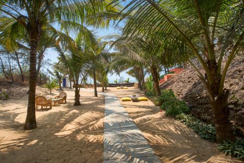 a pathway with palm trees on a sandy beach at Mandrem Beach Resort, a member of Radisson Individuals Retreat in Mandrem