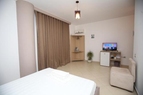 a room with a bed and a chair and a television at TekB Rooms & Apartments in Vlorë
