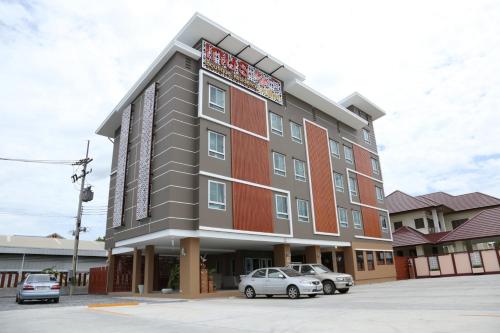 a building with cars parked in a parking lot at Kesorn Boutique Residence at 8 Riew in Chachoengsao