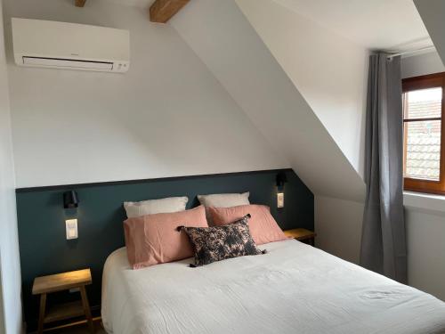 una camera da letto con un letto bianco e cuscini rosa di L'Adresse - Rempart Sud - Eguisheim avec garage privé a Eguisheim