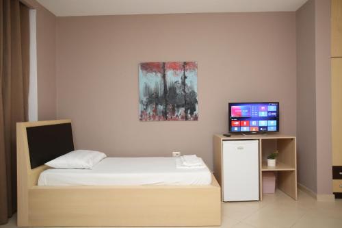 a small bedroom with a bed and a television at TekB Rooms & Apartments in Vlorë