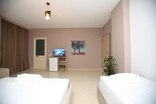a bedroom with two beds and a television in it at TekB Rooms & Apartments in Vlorë