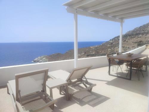 un patio con mesa, sillas y el océano en Sifnos "Sofia apartments" sea view, en Faros