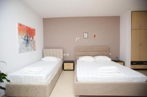 two beds in a room with white walls at TekB Rooms & Apartments in Vlorë
