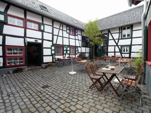 une cour avec des tables et des chaises dans un bâtiment dans l'établissement Nostalgic apartment in the Eifel region, à Schleiden