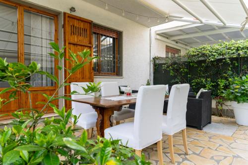 patio con tavolo in legno e sedie bianche di Villino Claudia a Forte dei Marmi