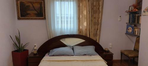 Schlafzimmer mit einem Bett mit einem Kopfteil aus Holz und einem Fenster in der Unterkunft Κατερινα in Athen
