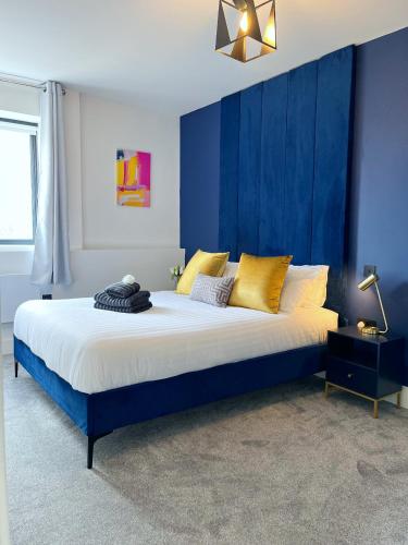 a bedroom with a large bed with blue walls at Luxury Norwich City Centre Flat - Free Parking in Norwich