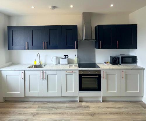a kitchen with white cabinets and a sink at Luxury Norwich City Centre Apartment - Free Parking in Norwich