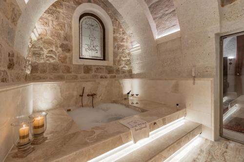 a large bathroom with a tub with candles in it at Via Regia Cappadocia Hotel in Uchisar
