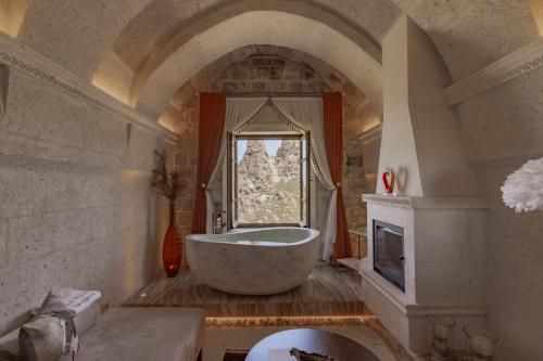 a bathroom with a large tub and a window at Via Regia Cappadocia Hotel in Uchisar