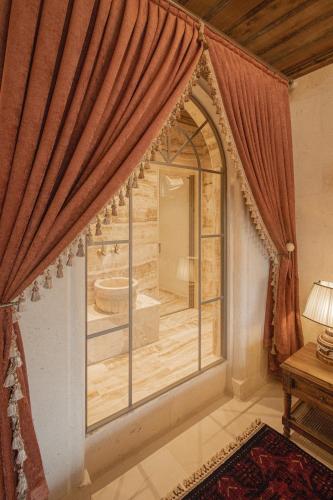a room with a large window with a tub inside at Via Regia Cappadocia Hotel in Uchisar