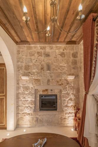 a living room with a stone wall with a fireplace at Via Regia Cappadocia Hotel in Uchisar