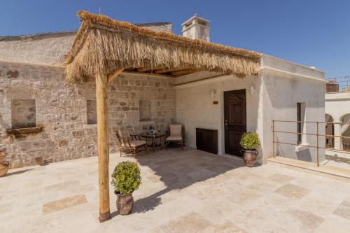 a large patio with a table and a straw roof at Via Regia Cappadocia Hotel in Uchisar