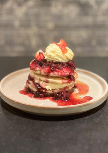 a stack of pancakes with berries and whipped cream on a plate at Hilton London Paddington in London
