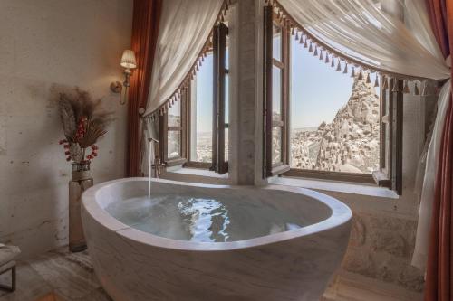 a large bath tub in a room with a window at Via Regia Cappadocia Hotel in Uchisar