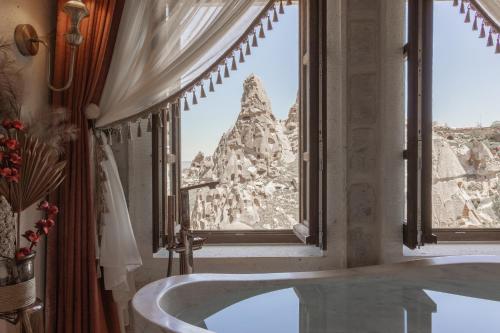 a bath tub in a bathroom with a view of a mountain at Via Regia Cappadocia Hotel in Uchisar