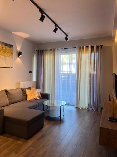 een woonkamer met een bank en een glazen tafel bij Apartament Augustynika in Dąbrowa Górnicza