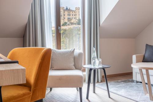 a living room with a chair and a table at AMERON Neuschwanstein Alpsee Resort & Spa in Schwangau