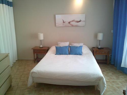 une chambre avec un lit blanc avec des oreillers bleus dans l'établissement Vittoria immobilier-PACIFIC PLAGE - Chèques Vacances acceptés., à La Grande Motte