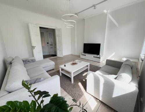 een woonkamer met witte meubels en een televisie bij Słoneczny Apartament w Centrum in Słupsk