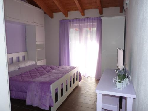 a bedroom with a purple bed and a window at B&B Il Barsot in Pettenasco