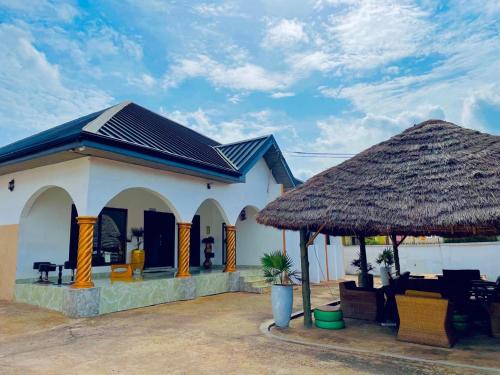 un pequeño edificio blanco con techo de paja en Nana's Holiday Let en Accra