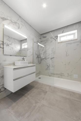 a white bathroom with a sink and a shower at 3BR Oasis With Pool by LovelyStay in Vale Covo