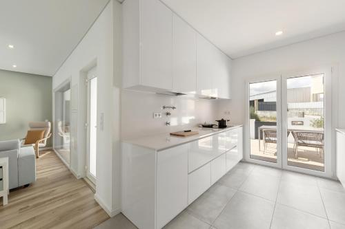 a white kitchen with white cabinets and a table at 3BR Oasis With Pool by LovelyStay in Vale Covo