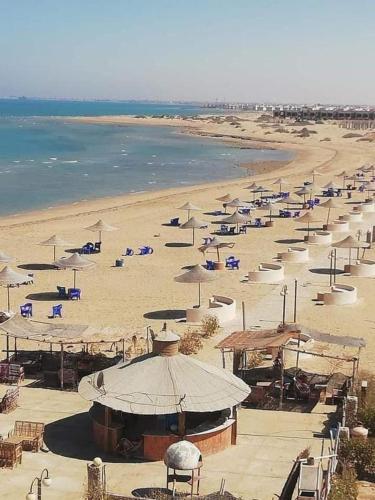 una spiaggia con ombrelloni e sedie e l'oceano di شالية غرفة قرية بلولاجون a Ras Sedr