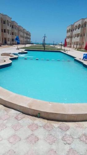 una gran piscina de agua azul frente a los edificios en شالية غرفة قرية بلولاجون en Ras Sedr