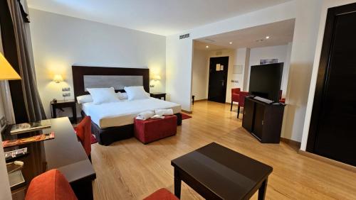 um quarto de hotel com uma cama e uma sala de estar em Las Bóvedas em Badajós
