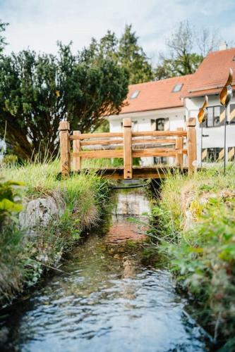 a wooden bridge over a stream in front of a house at Lake house with sun terrace for 8 guests in Herrsching am Ammersee