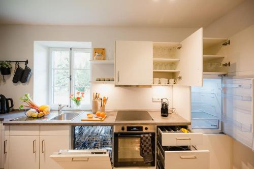 a kitchen with white cabinets and a sink at Lake house with sun terrace for 8 guests in Herrsching am Ammersee