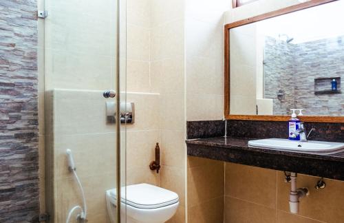 La salle de bains est pourvue de toilettes, d'un lavabo et d'un miroir. dans l'établissement Harmony Homes Beachfront, à Diani Beach