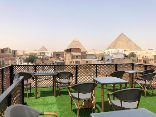 a balcony with tables and chairs and the pyramids at Nefertari pyramids inn in Cairo