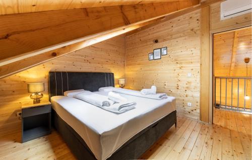 - un grand lit dans une chambre dotée de murs en bois dans l'établissement Awesome Home In Bilje With Outdoor Swimming Pool, à Bilje