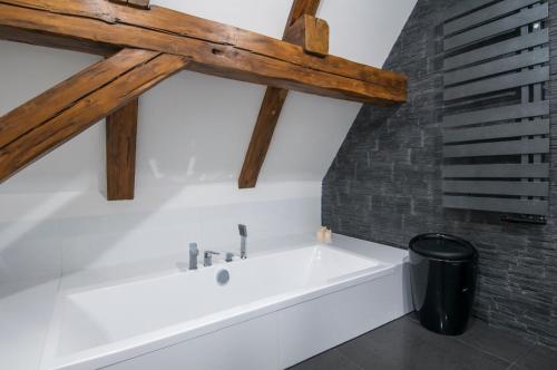 a white bath tub in a bathroom with wooden beams at Roof Apartment in Wrocław