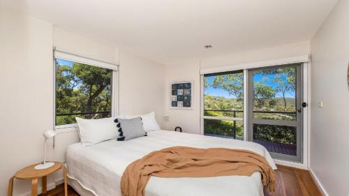 a bedroom with a bed and two windows at 'Allure' by HolidayCo in Killcare