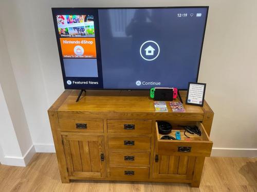 a television on top of a wooden dresser at The Farmhouse at Moss Bank Farm in Wrexham