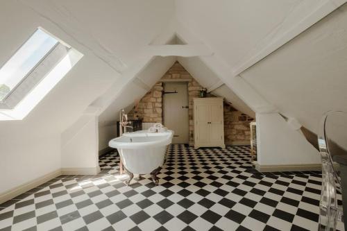 a bathroom with a white tub and a checkered floor at The Old Stables in Newcastle upon Tyne