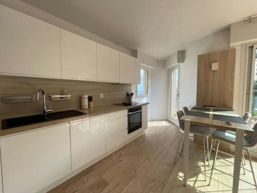 une cuisine avec des armoires blanches et une table à l'intérieur dans l'établissement Bellavista, à Beausoleil