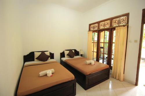two beds in a room with a window at Jepun Bali Bungalow in Nusa Lembongan