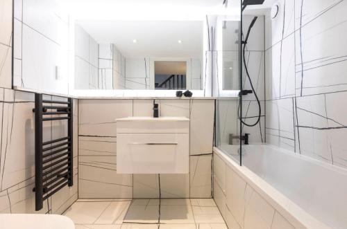 een witte badkamer met een bad, een wastafel en een bad bij Palm Tree House - Angles Max in Orpington