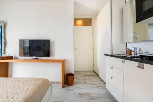 um quarto com uma cama e uma cozinha com uma televisão em 010 Studio City Center Rotterdam em Roterdã