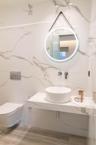 a white bathroom with a sink and a mirror at Missiria Apartments in Rethymno Town