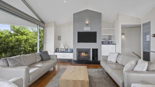 a living room with a couch and a fireplace at 'A Beachside Getaway - 8' by HolidayCo in Killcare