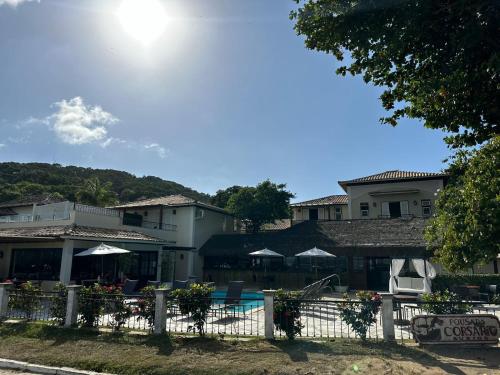 ein Resort mit einem weißen Zaun sowie Tischen und Sonnenschirmen in der Unterkunft Pousada Corsario Buzios in Búzios