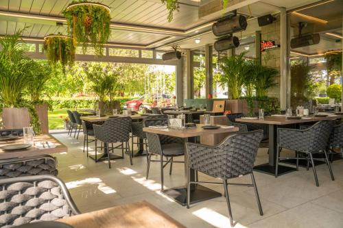 un restaurante con mesas, sillas y plantas en Exclusive Hotel & More, en Sibiu